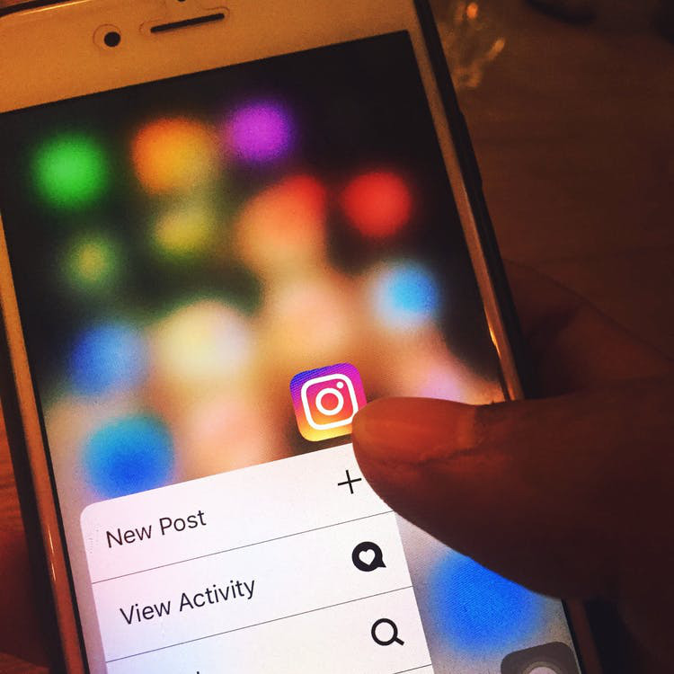 A person touches the Instagram app icon on their iPhone opening the dropdown menu