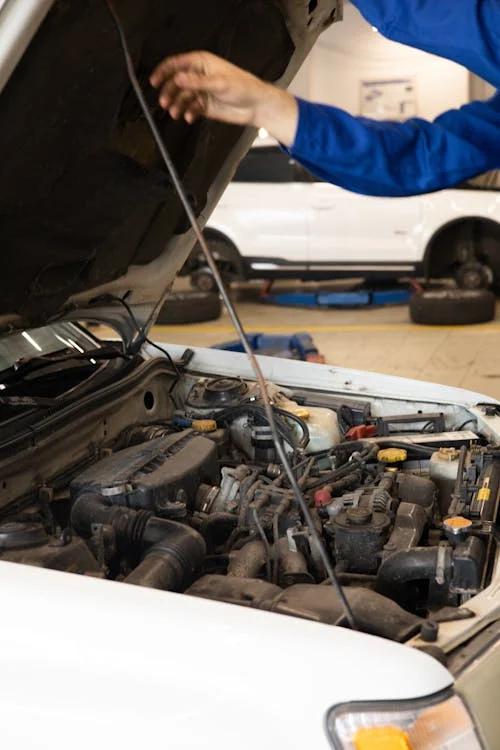 A mechanic working on a car engine inside an auto repair shop.