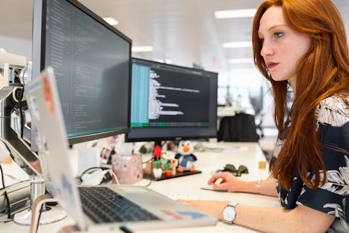 A woman using multiple screens at work