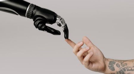A human hand and a robotic hand point fingers at each other